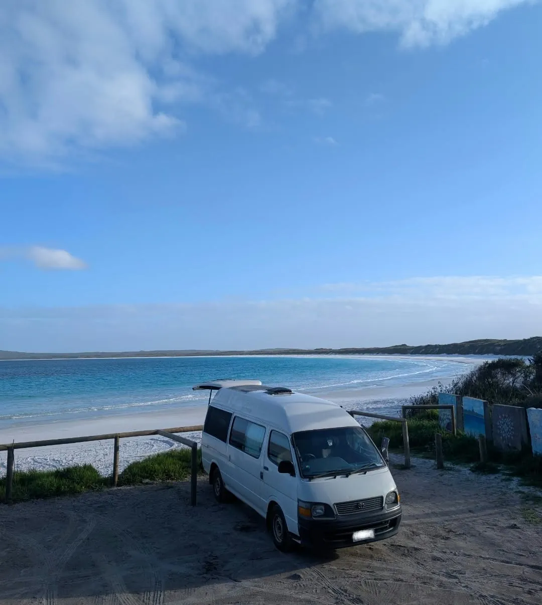 Hank parked at a lookout above a white-sand beach and blue bay